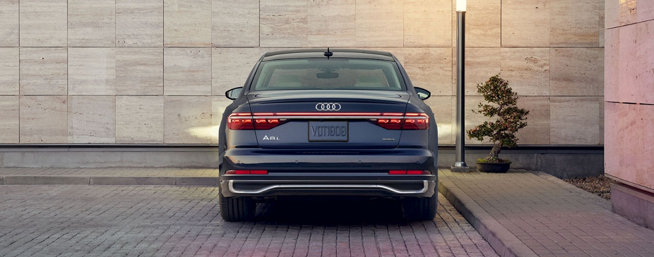 A dark blue 2024 Audi A8 on a brick lot.